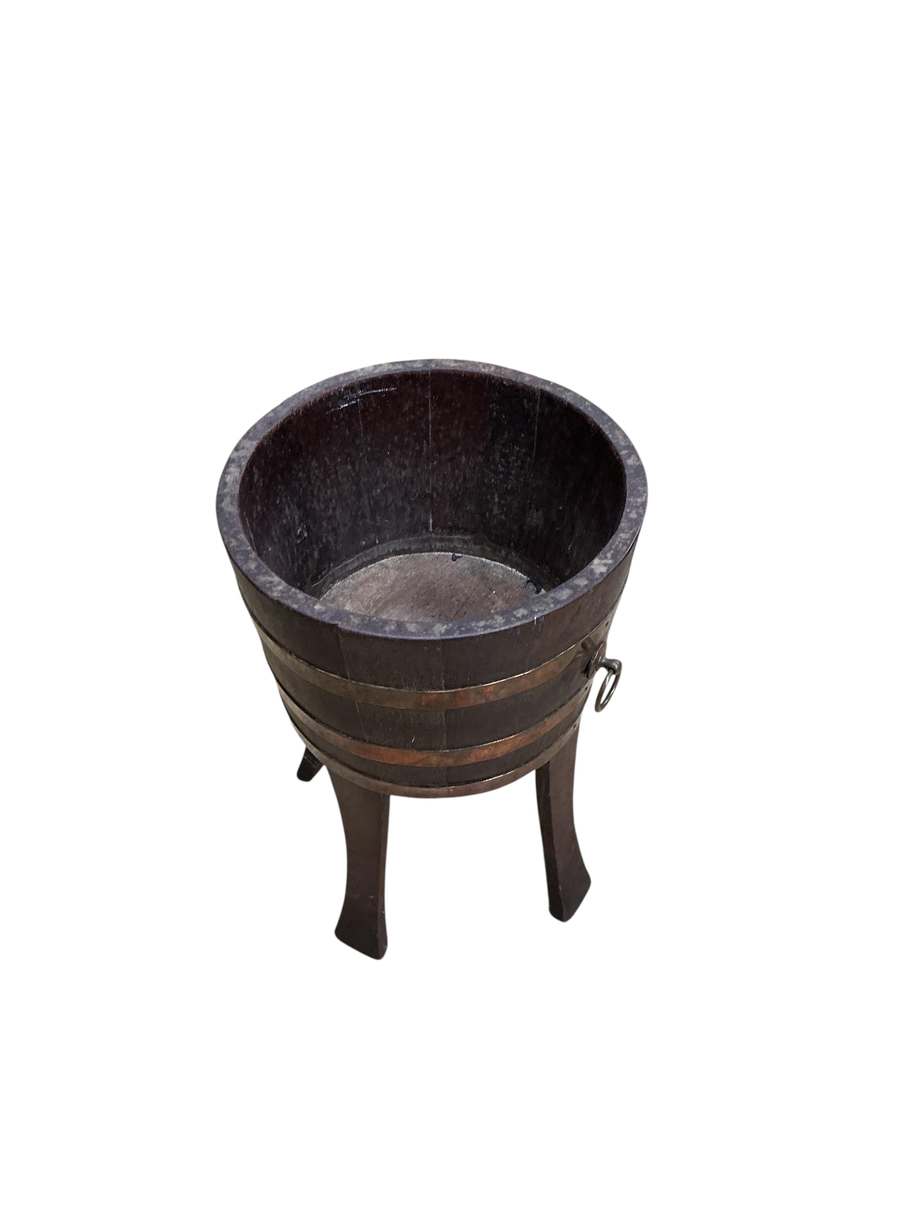 A copper bound staved oak circular jardiniere, late 19th century, maker's stamp Champion RD, diameter 33cm, height 53cm